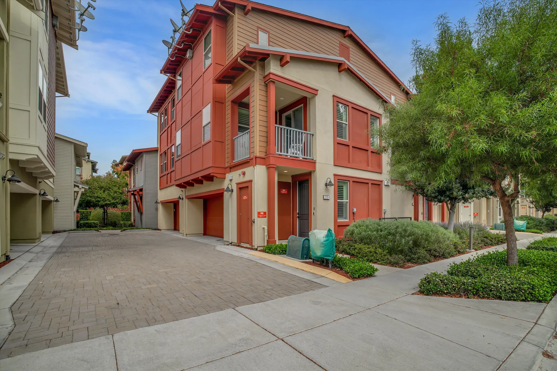 Red-and-tan exterior of 772 Tranquility Circle #1 beside the paved drive and landscaped walkway