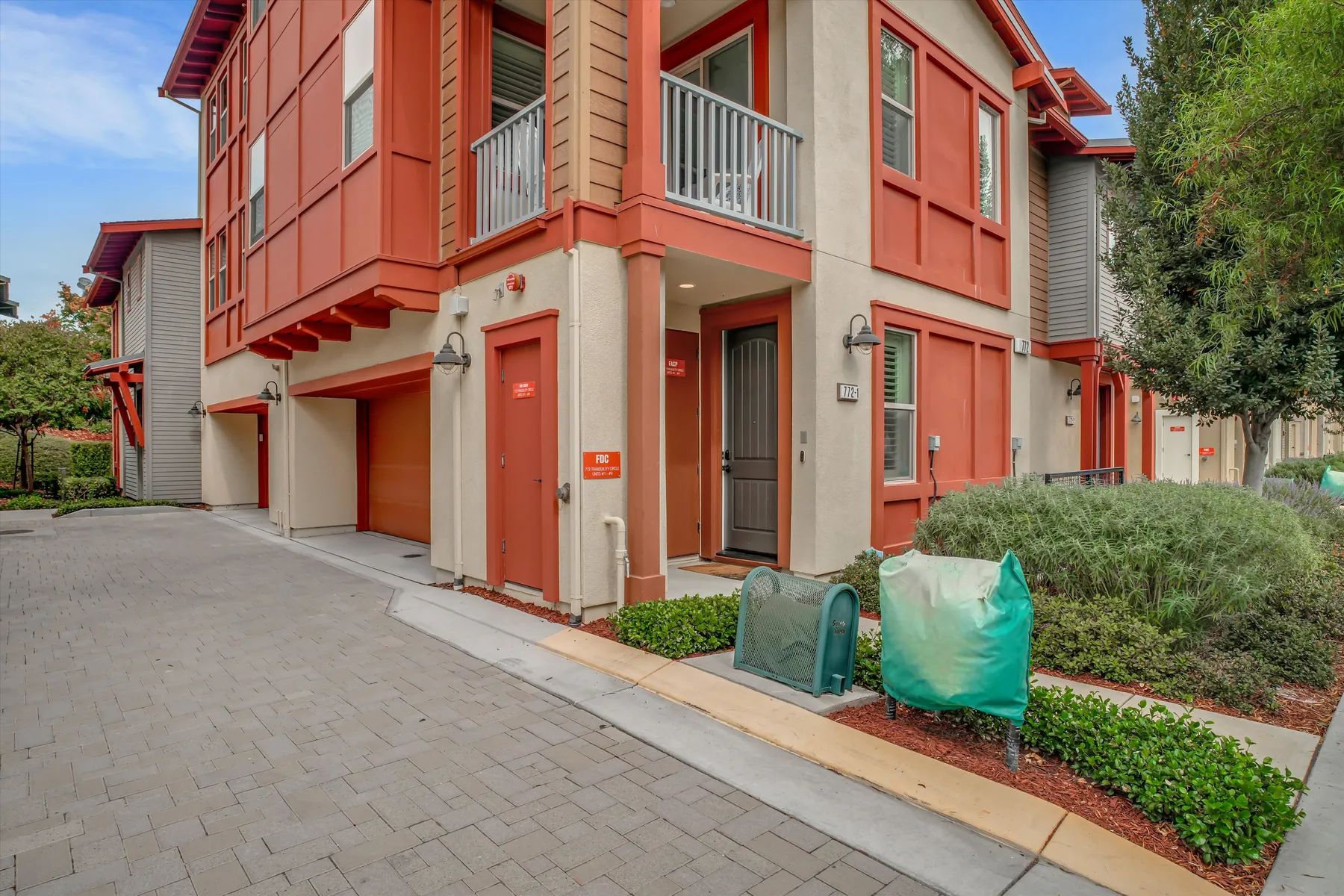 Corner view of the red condominium building, garage doors and entry walkway