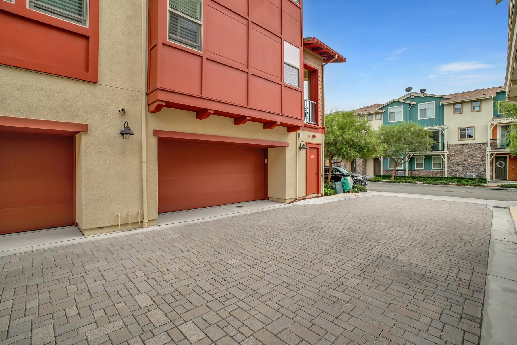 Two-car garage door at ground level below the red exterior and covered balcony