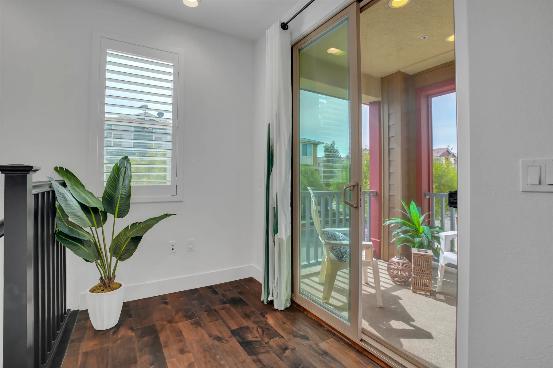 Interior view of the glazed balcony door beside a potted plant and shuttered window