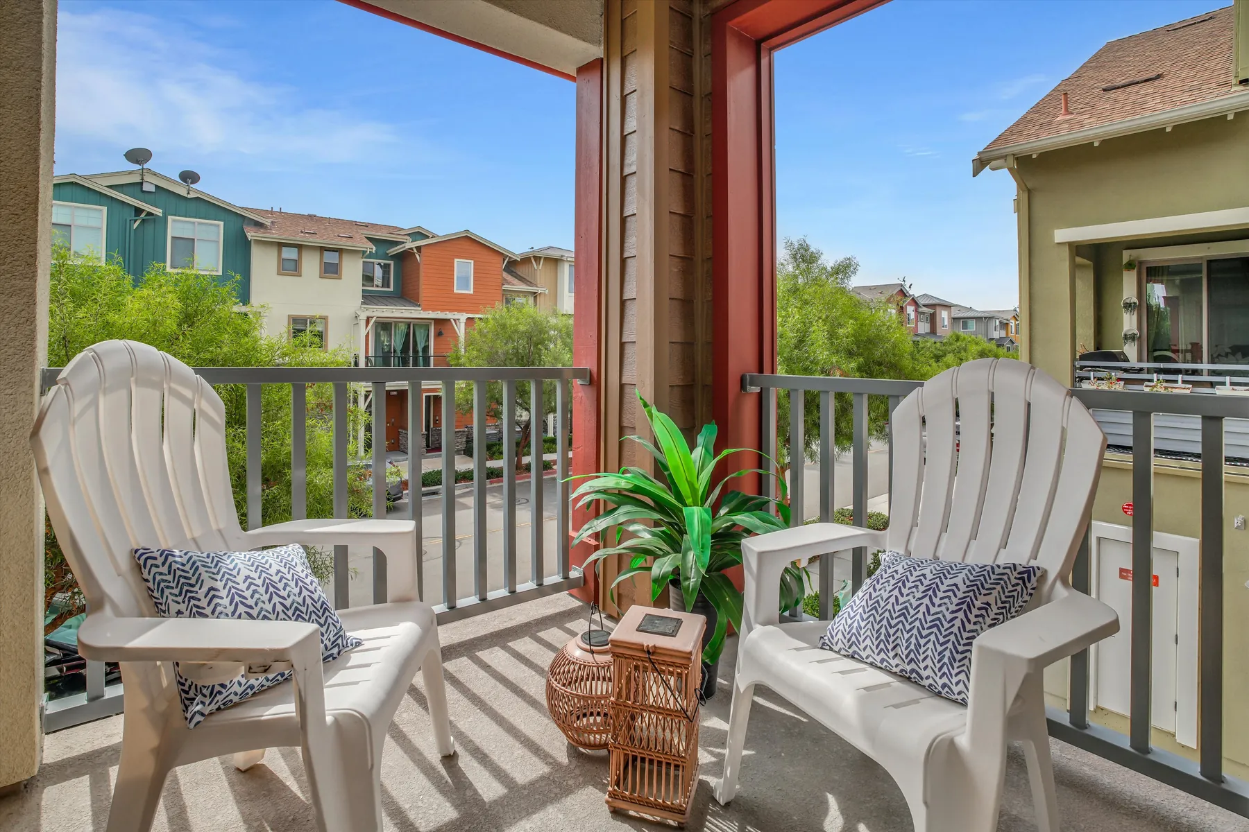 Covered balcony with two white chairs, a small side table and views of nearby Sage homes