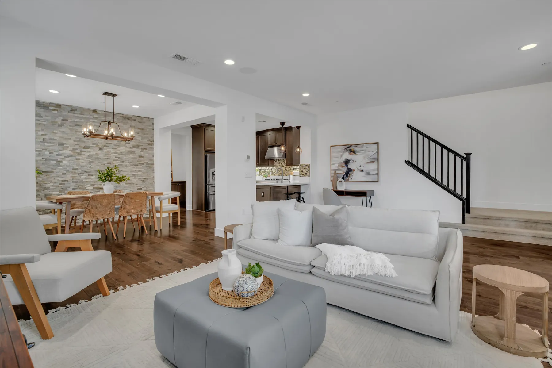 Living room seating facing the dining area, kitchen island and staircase