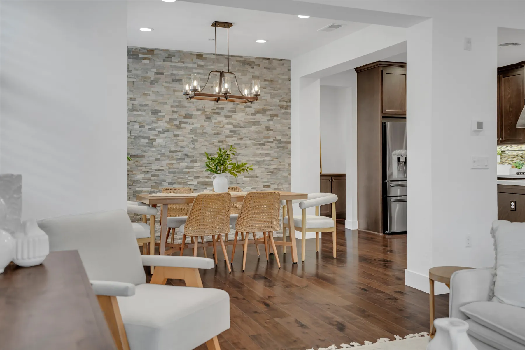 Dining area with stone-textured accent wall and hanging light fixture beside the living room