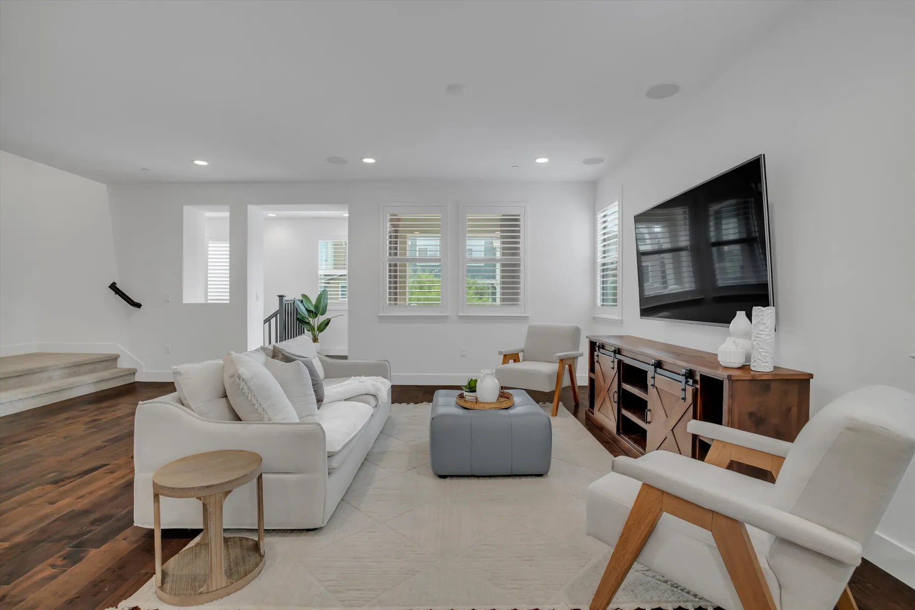 Living room with shuttered windows, sofa, television console and open floor area