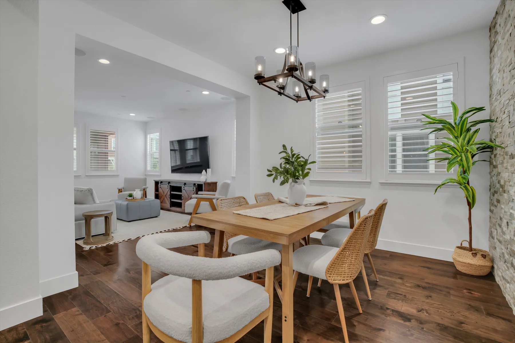 Dining table under a geometric chandelier with sightline to the living room